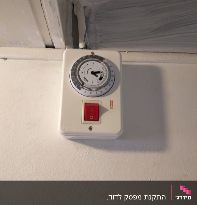 שעון טיימר חשמלי עם מתג אדום על קיר